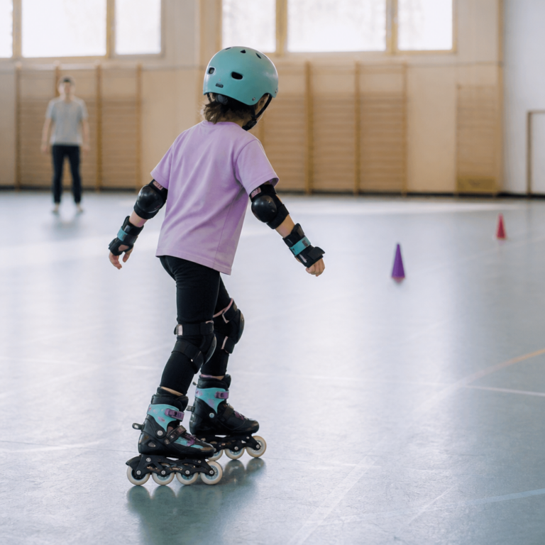 Kind mit Schutzausru00fcstung beim sicheren Rollschuhtraining in einer Halle